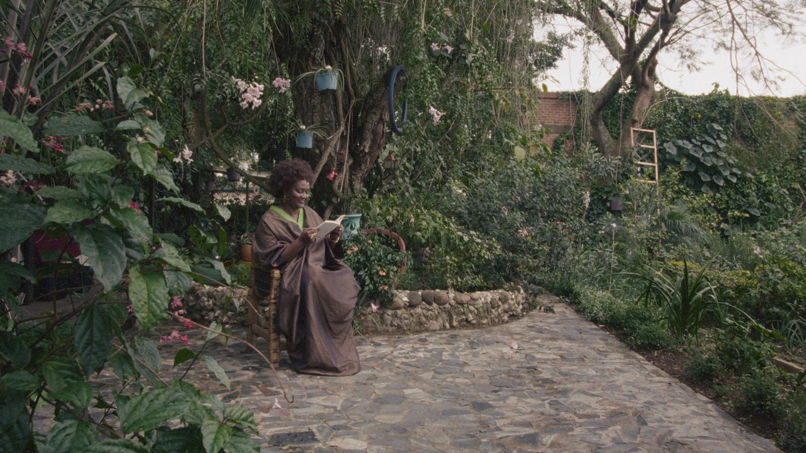 Alice Karekezi lisant dans un jardin, image tirée du film KUBANA