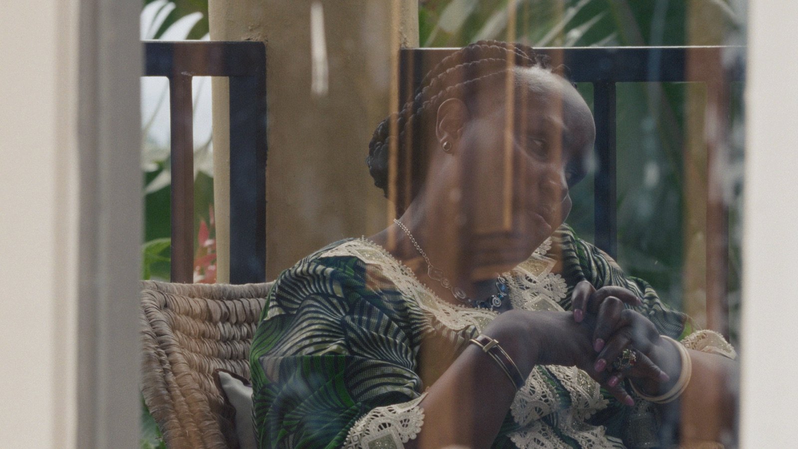 Émilienne Mukansoro vue à travers une fenêtre, image tirée du film KUBANA